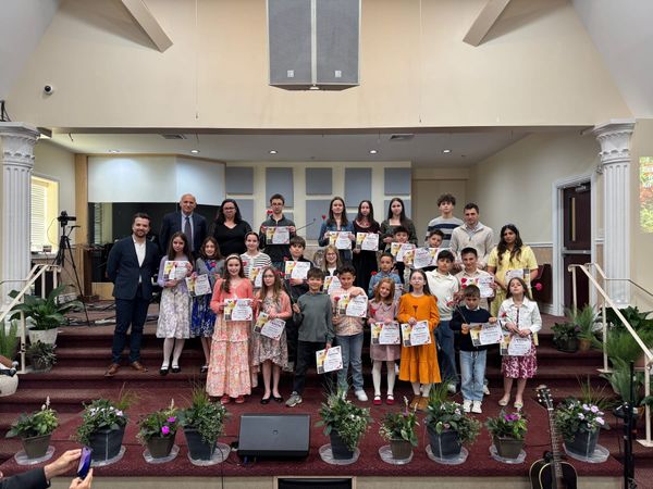 Sunday School students holding their certificates on stage with their teachers