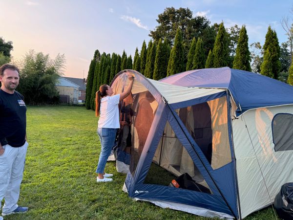 A family setting up a large tent on the lawn
