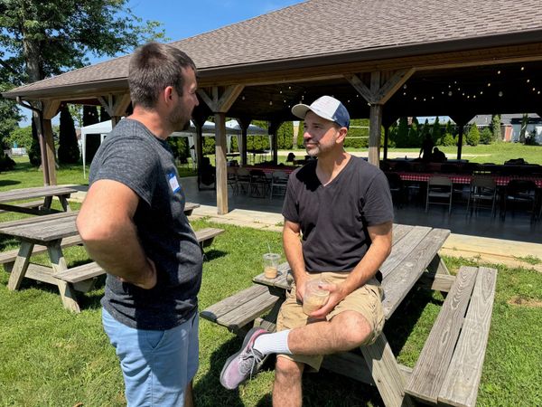 Two men talking at a picnic table in the park