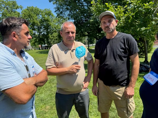 Three men chatting outdoors on a sunny day