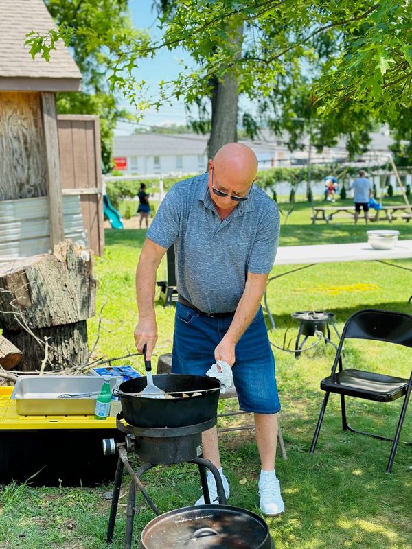 A man stirring a pot on an outdoor burner